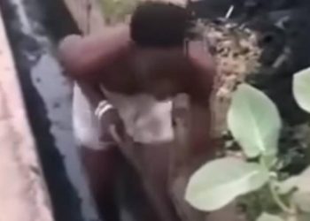 un homme présenté comme un présumé voleur contraint de curer un caniveau obstrué tout en étant forcé de danser