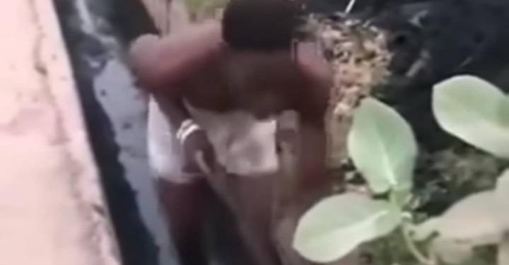 un homme présenté comme un présumé voleur contraint de curer un caniveau obstrué tout en étant forcé de danser